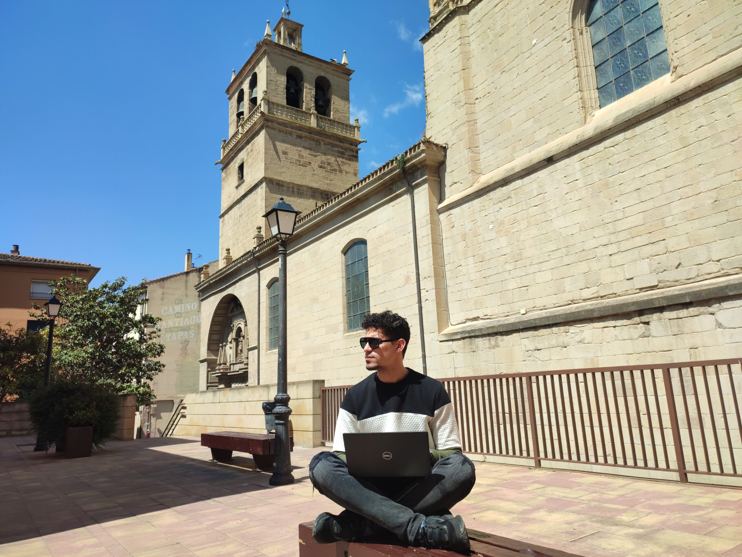 a person sitting on a sidewalk with a laptop